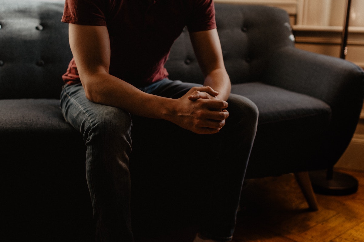 man sitting on a couch with hands clasped together