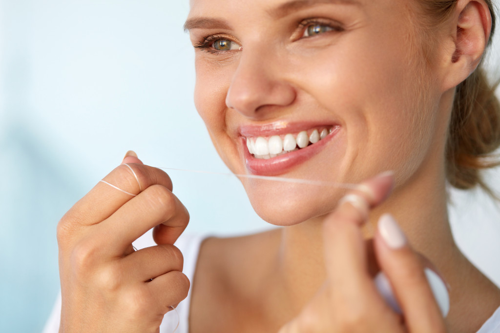 A person smiling while holding floss in her hands