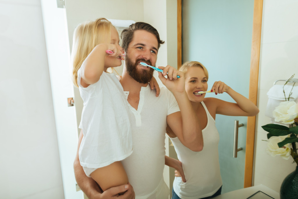 a happy family brushing their teeth in front of a mirror