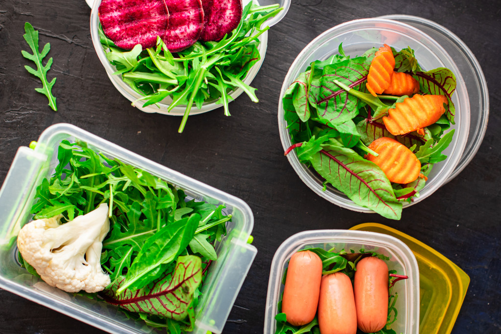 salads of different types in differently-shaped containers in a wooden table