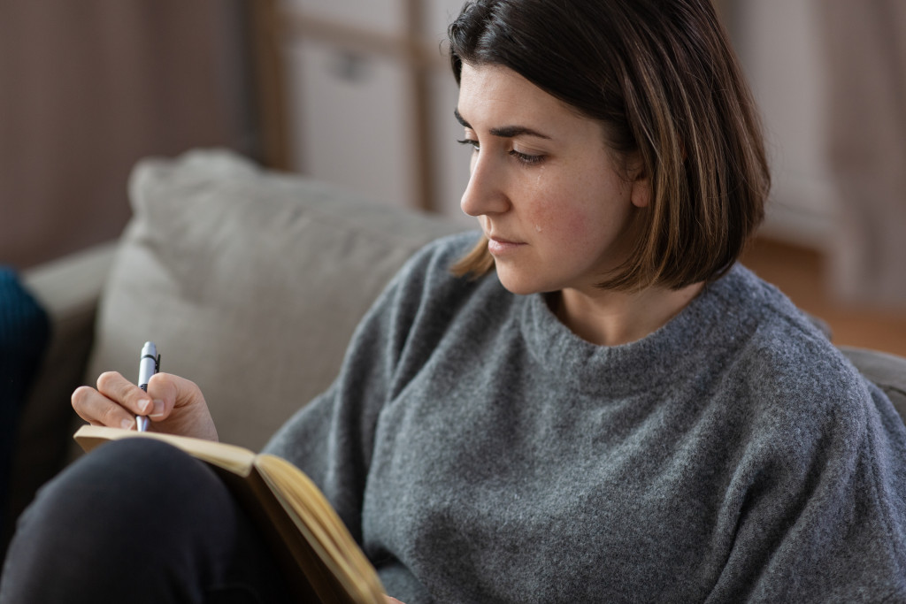 woman crying while journaling in her home